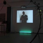 installation view with 2 video projections and a curved branch with speakers